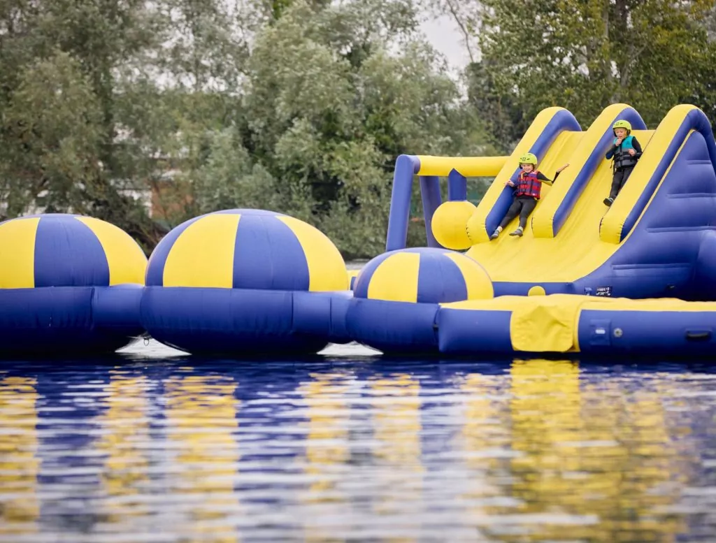 Children sliding into the water from the inflatable aqua park assault course at Billing Aquadrome.