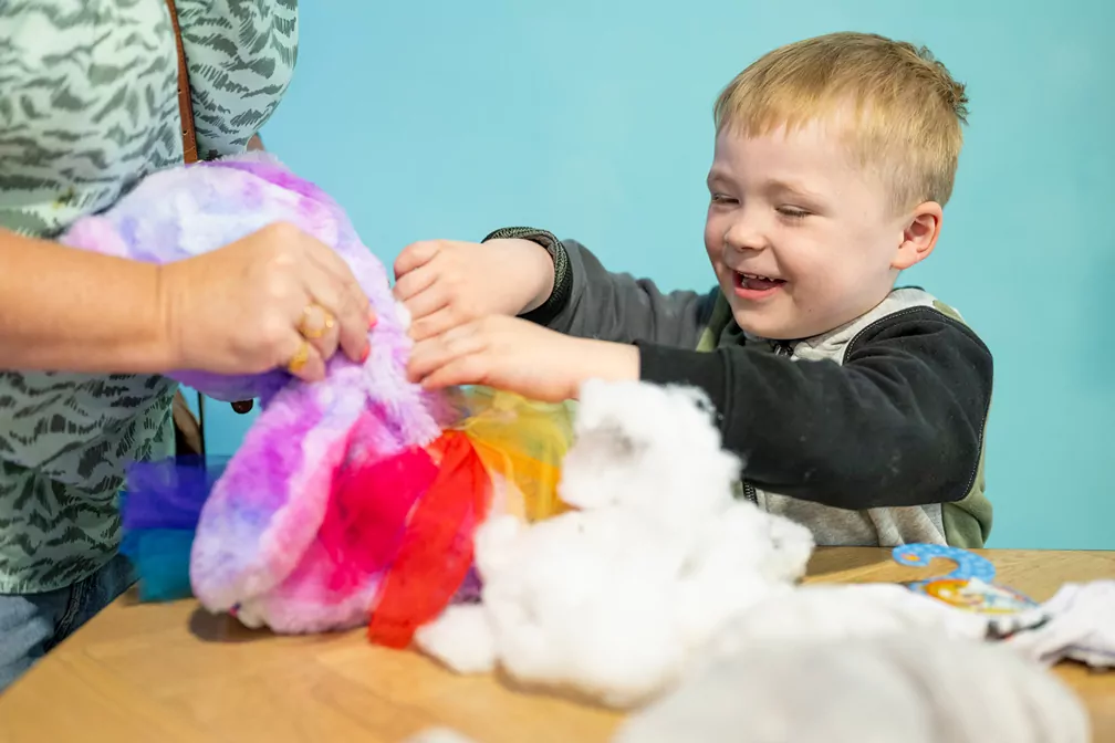 Young child enjoying colourful sensory play activity with soft toys at the Tribe Den at Billing Aquadrome