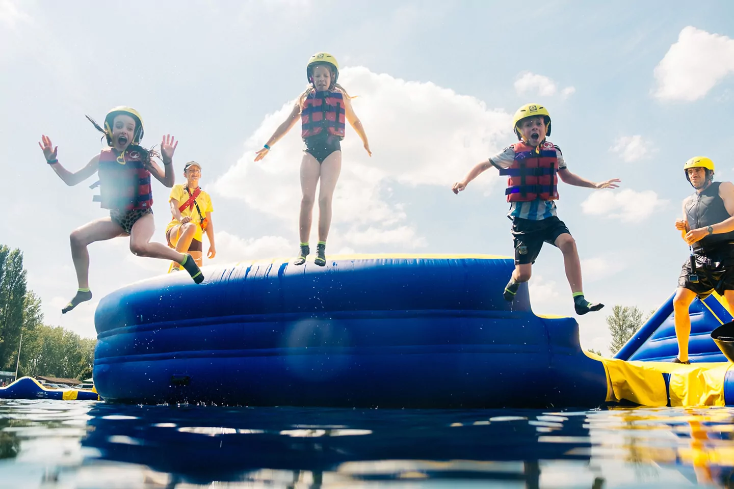 Children jumping into the water from an inflatable aqua park obstacle course at Willow Lake at Billing Aquadrome