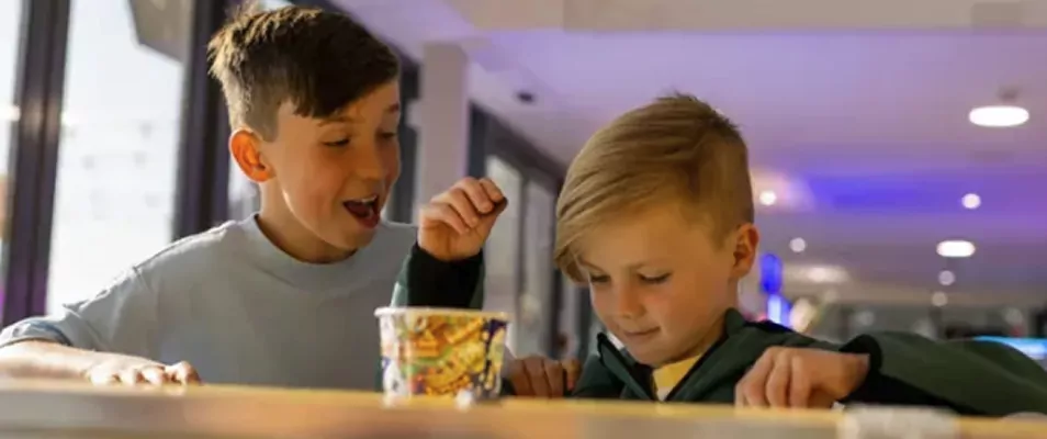Two young boys smiling and enjoying a tub of ice cream during a family break at Billing Aquadrome.