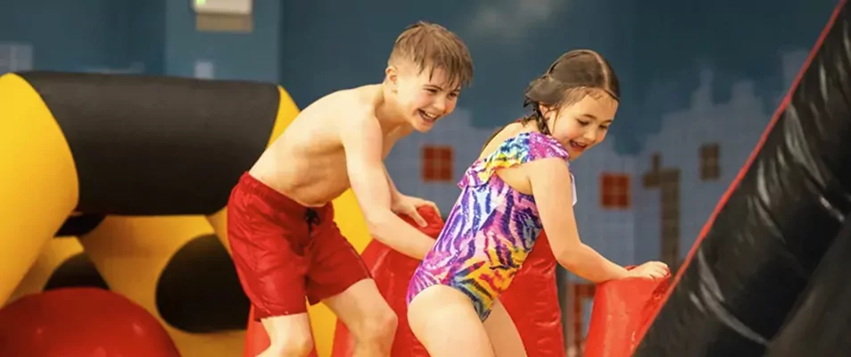 Children laughing and playing on indoor swimming pool inflatables at Billing Aquadrome.