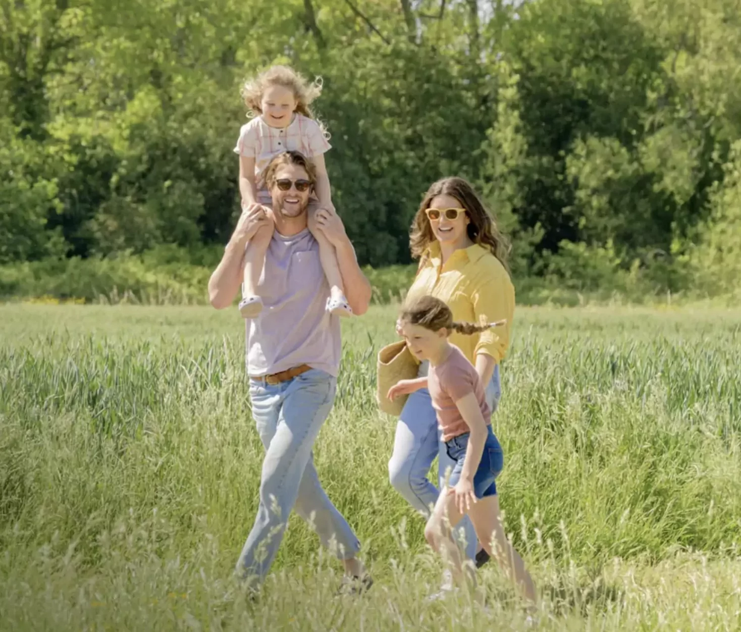 A happy family walking together through a sunny green field