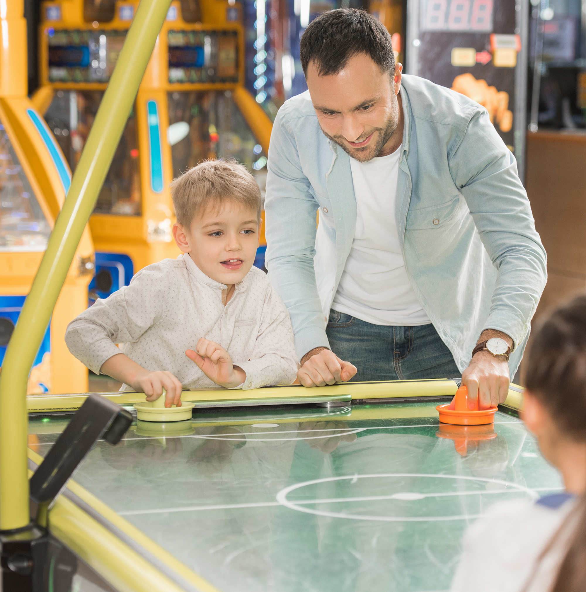 Father and children enjoying a fun game of air hockey together at Golden Leas.
