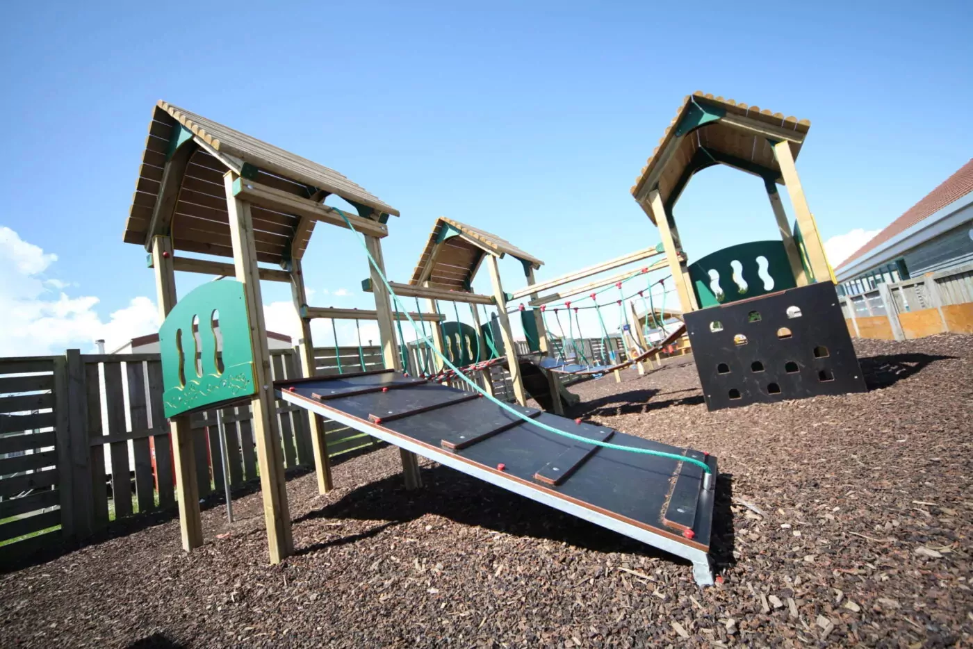 Outdoor wooden playground with climbing structures and slides at Golden Leas.