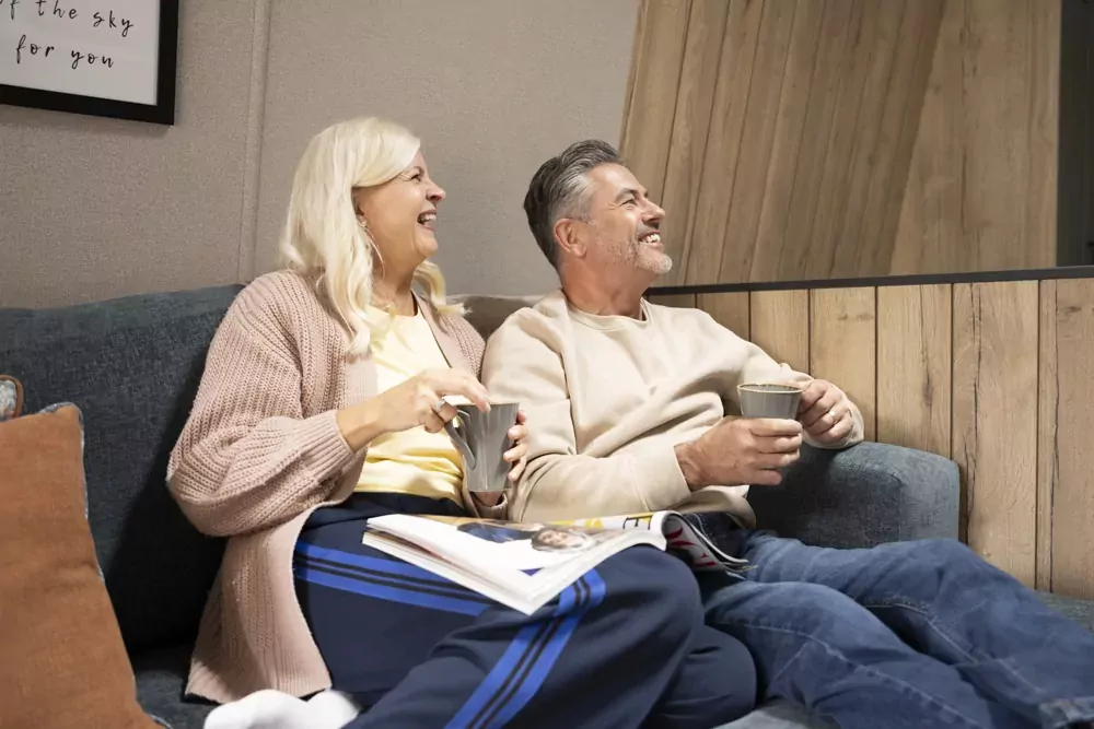Smiling couple enjoying coffee and quality time inside their holiday home at Meadow Bay Villages.