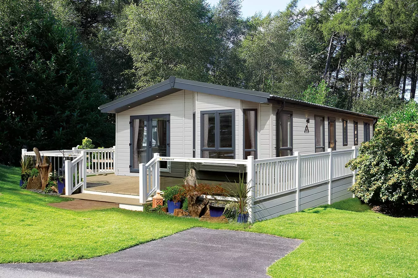 Exterior of the Lilac Lodge holiday home set in greenery at Meadow Bay Villages, with decking and white railing.