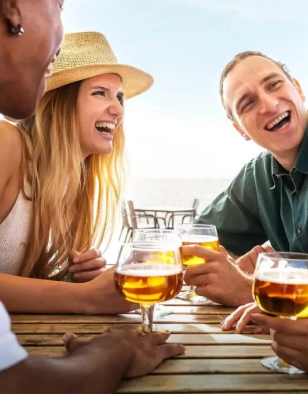 A group of friends laughing and enjoying drinks together on an outdoor patio at Golden Leas