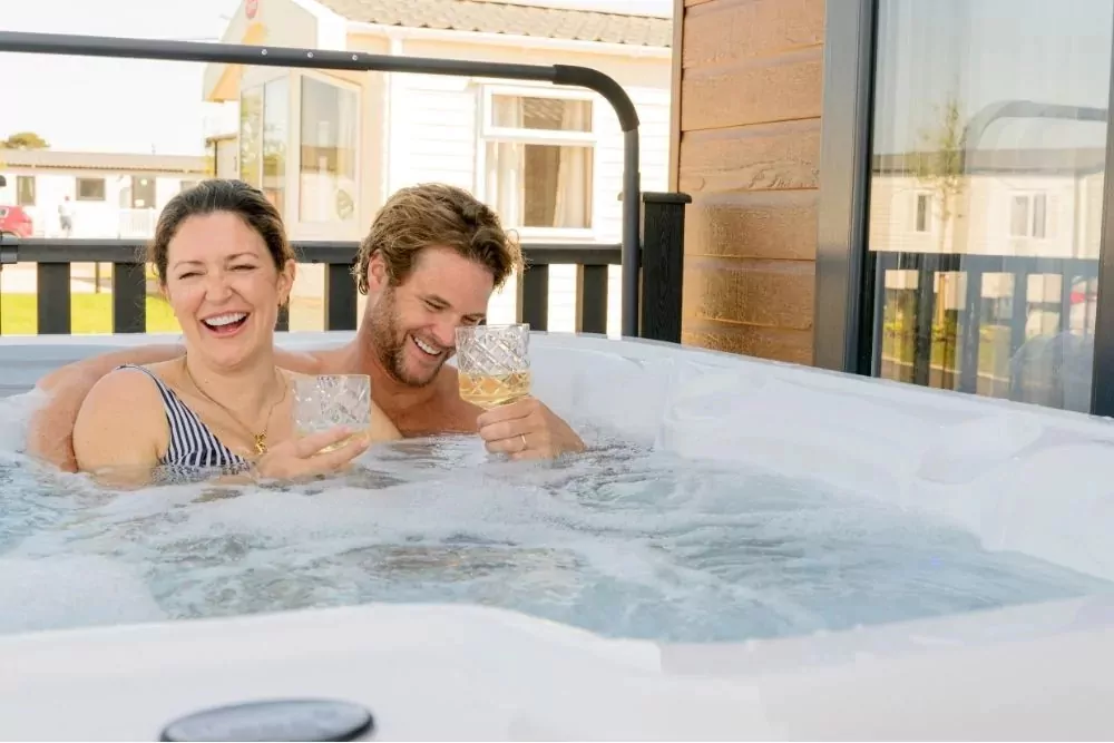 Guests relaxing together in an outdoor hot tub beside a holiday lodge while enjoying a getaway at Hayling Island.