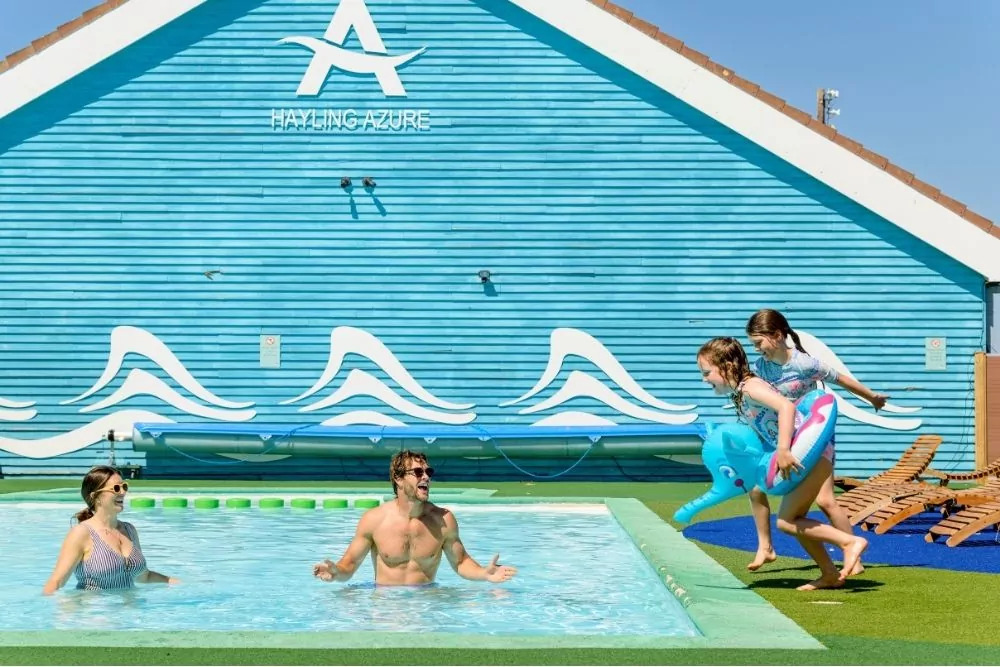 Family swimming and children jumping into the outdoor lido pool on a sunny day at Hayling Island.