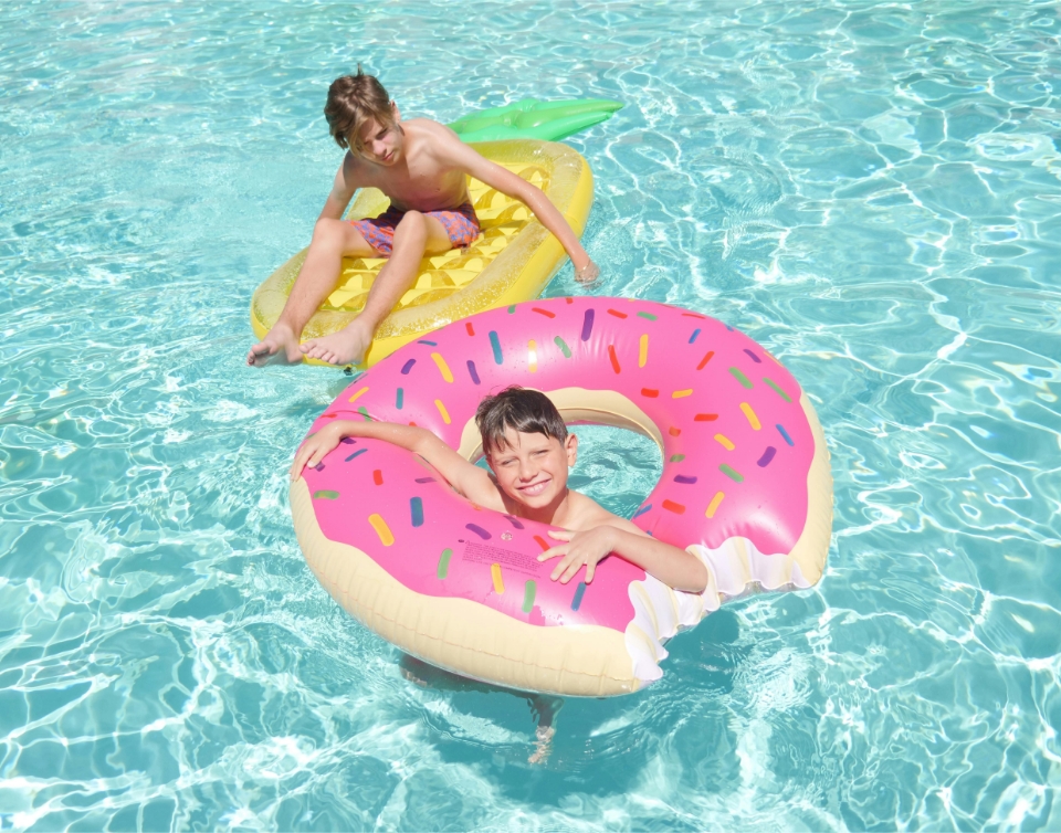 Two kids playing in inflatable rings in a pool