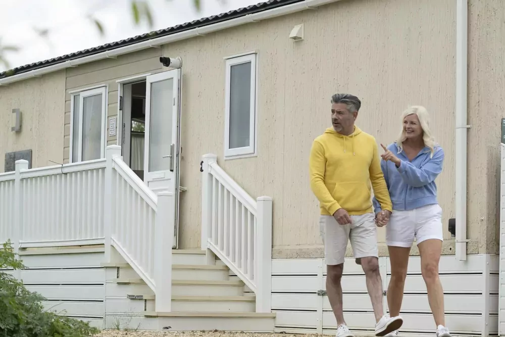 A smiling couple walking hand in hand outside their holiday home, enjoying a relaxed day at Hayling Island.