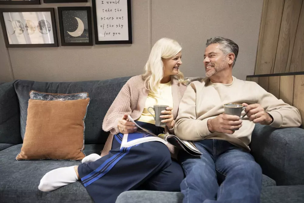 A relaxed couple enjoying coffee and a quiet moment together inside their holiday caravan on Hayling Island.