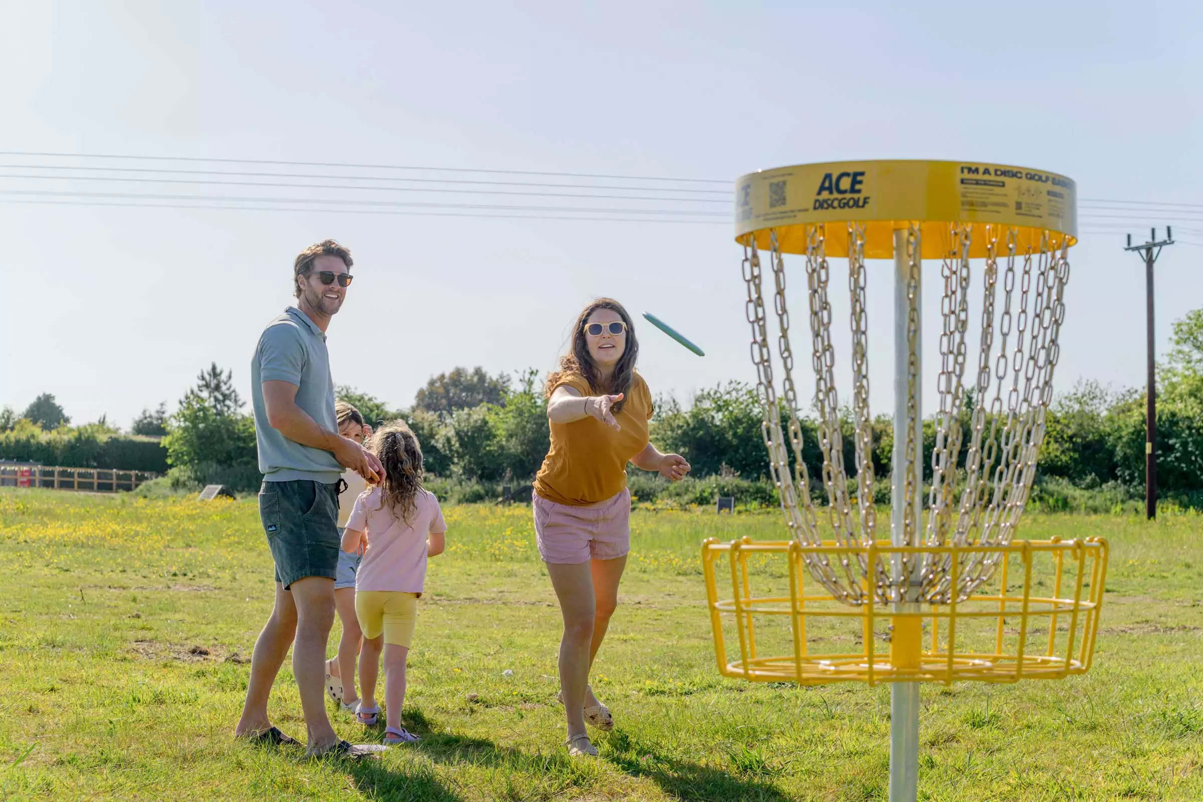 A family enjoying a fun game of disc golf together in the open grassy fields on Hayling Island.