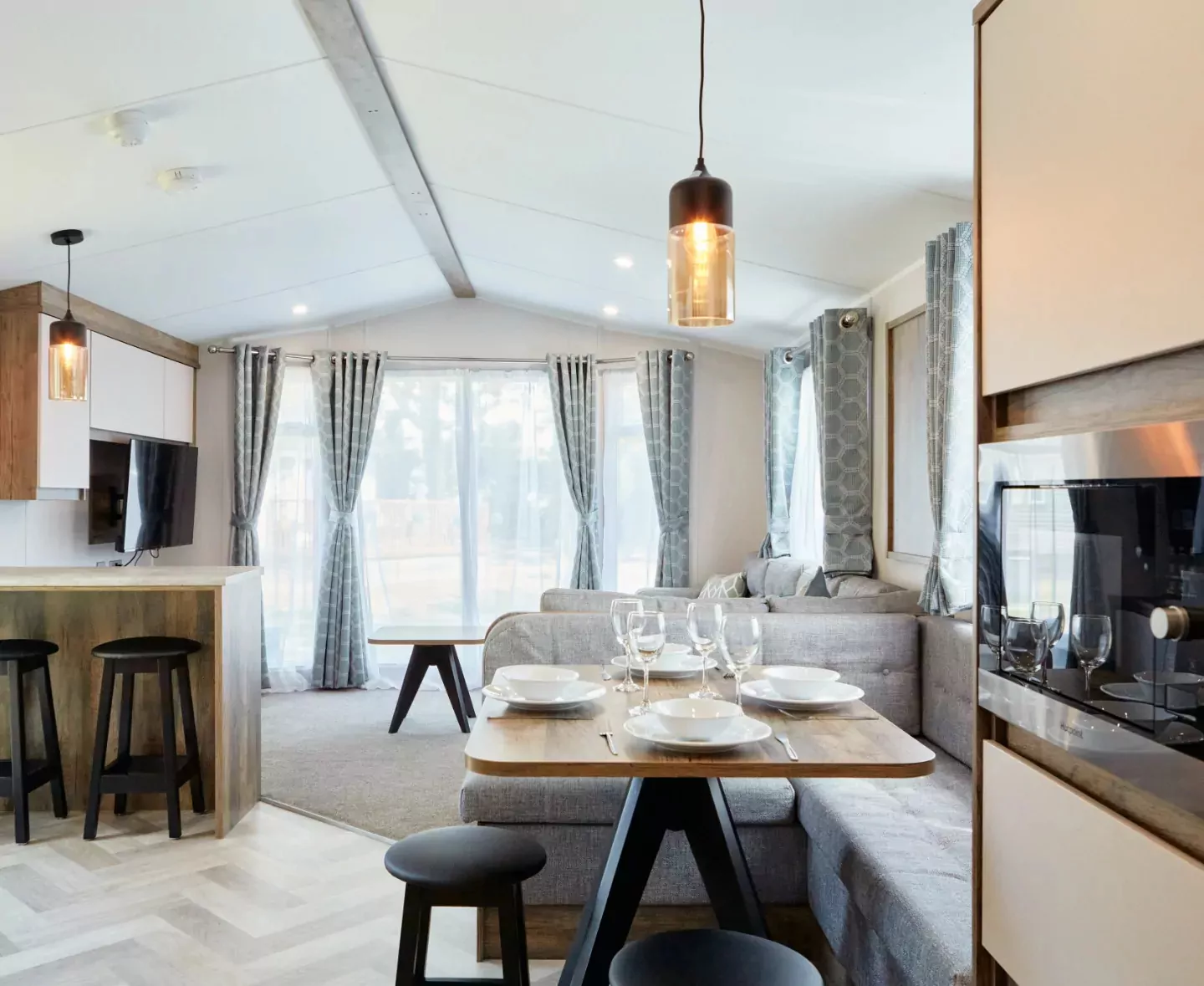 A spacious and modern open-plan living area in a holiday home, featuring a dining table and comfortable lounge seating Hayling Island