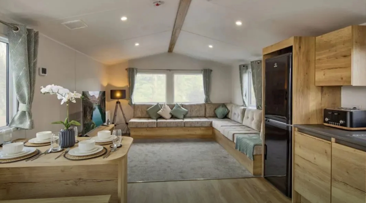 A spacious silver caravan at Hayling Island with a large corner sofa and modern kitchen.