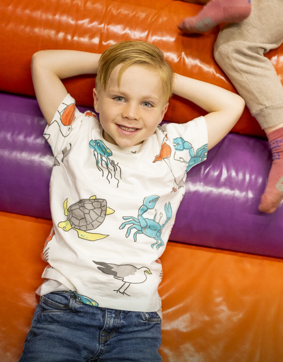 A happy boy lying back and relaxing on colourful soft play equipment in Hayling Island.