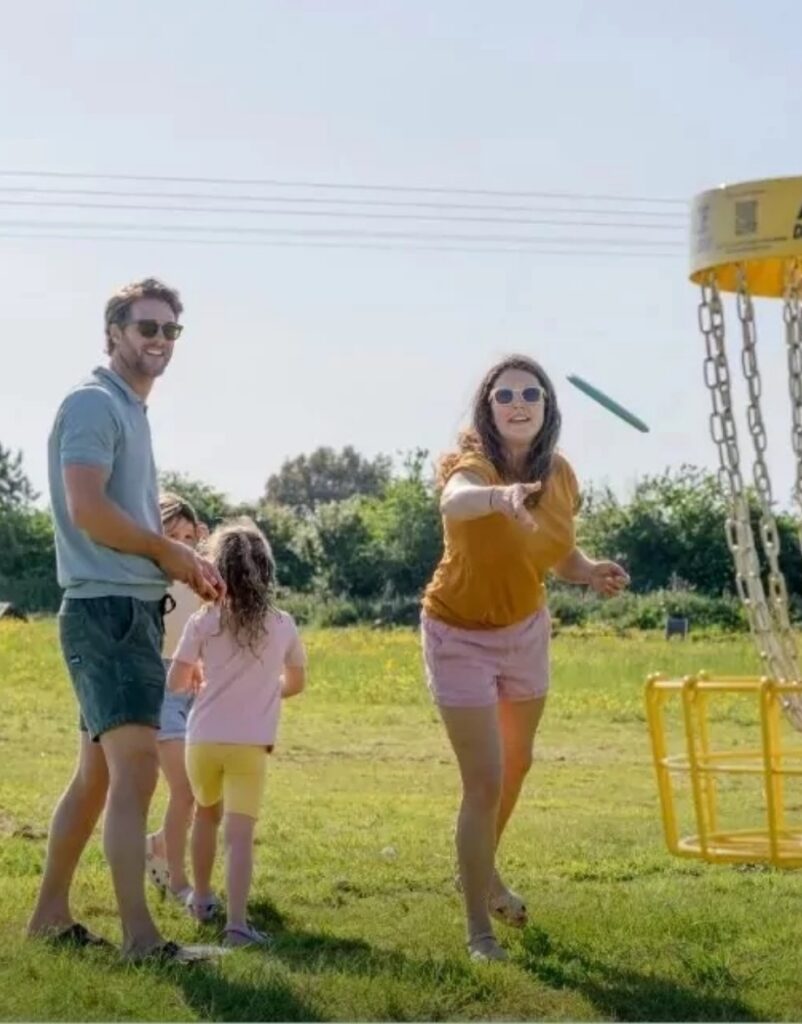 Family enjoying a game of disc golf together in open green space at Billing Aquadrome