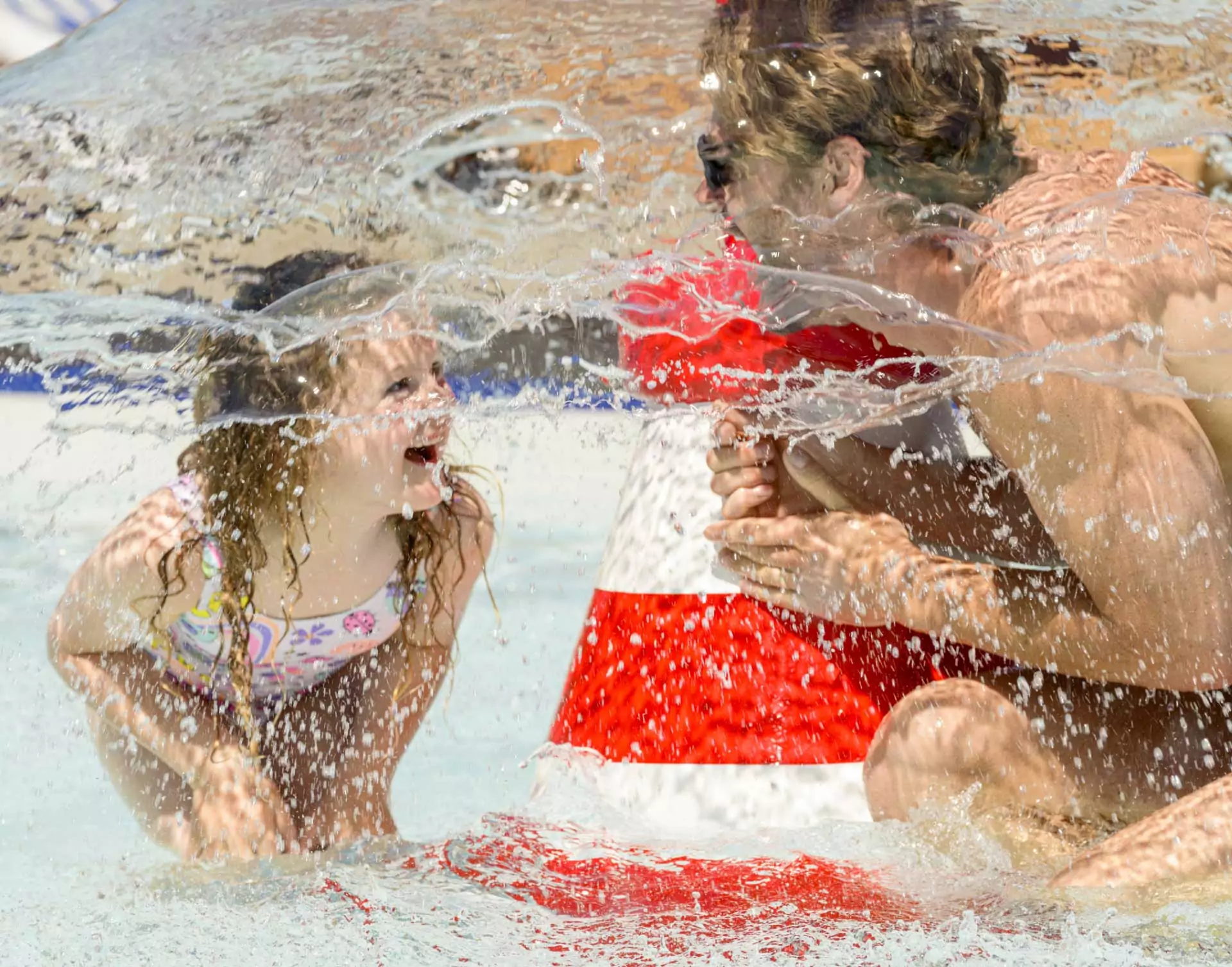 A child laughs as water sprays from a feature in the outdoor splash park at Hayling Island.