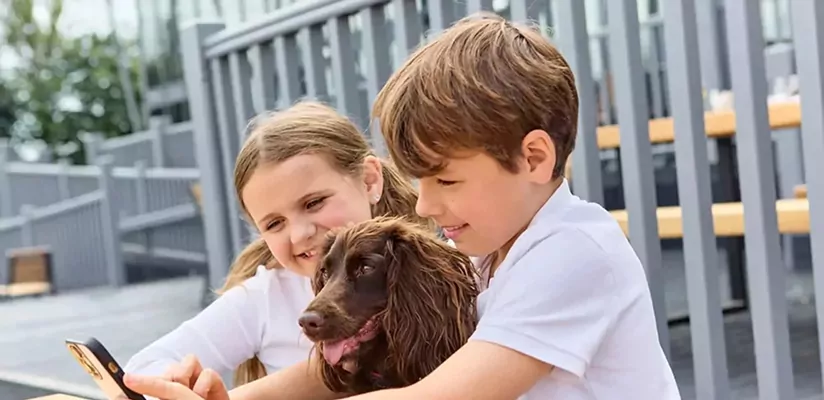 Two children sitting outside holiday accommodation with a family dog, Hayling Island