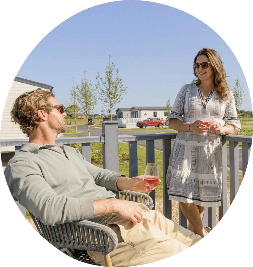 Couple relaxing with drinks on the decking outside a holiday caravan on a sunny day at Hayling Island.