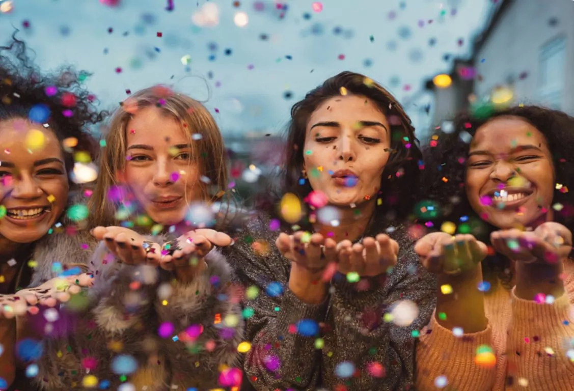 Friends celebrating and throwing colourful confetti during a fun event at Hayling Island