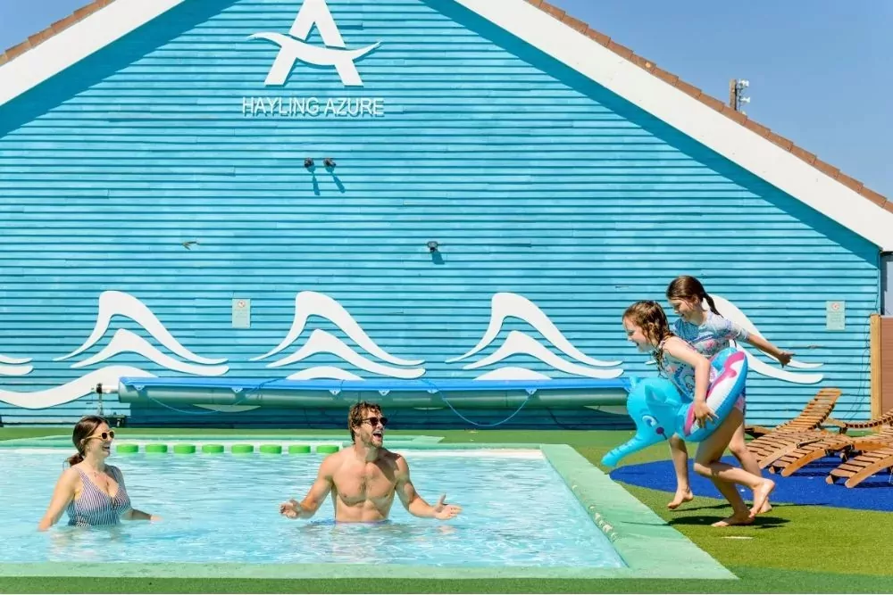 Family swimming and children jumping into the outdoor lido pool on a sunny day at Hayling Island.