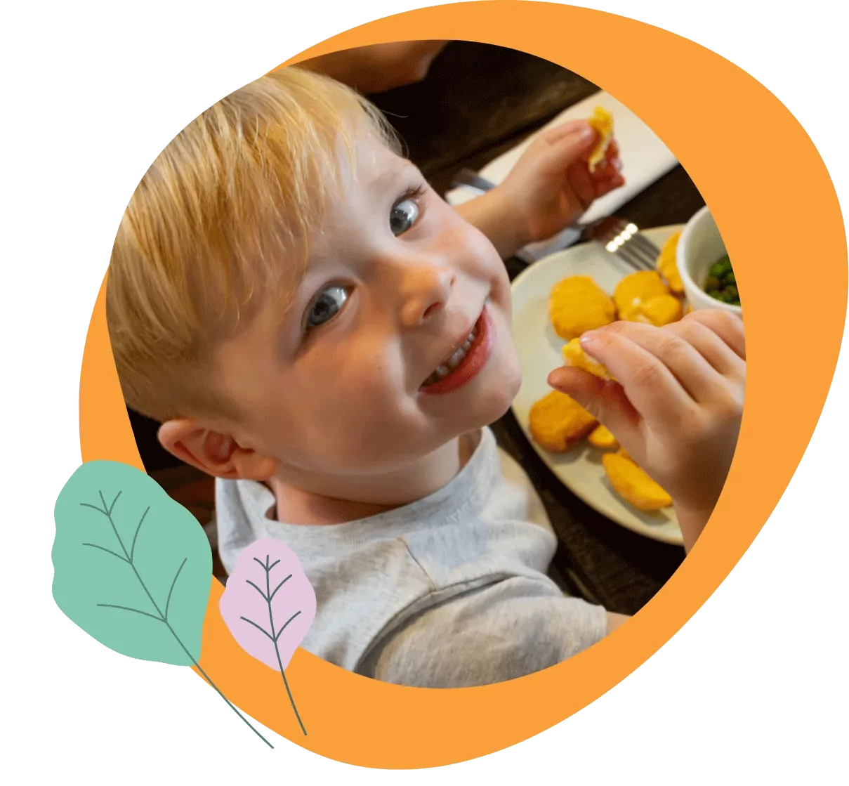 A young child smiling and enjoying a meal of chicken nuggets and chips Hayling Island