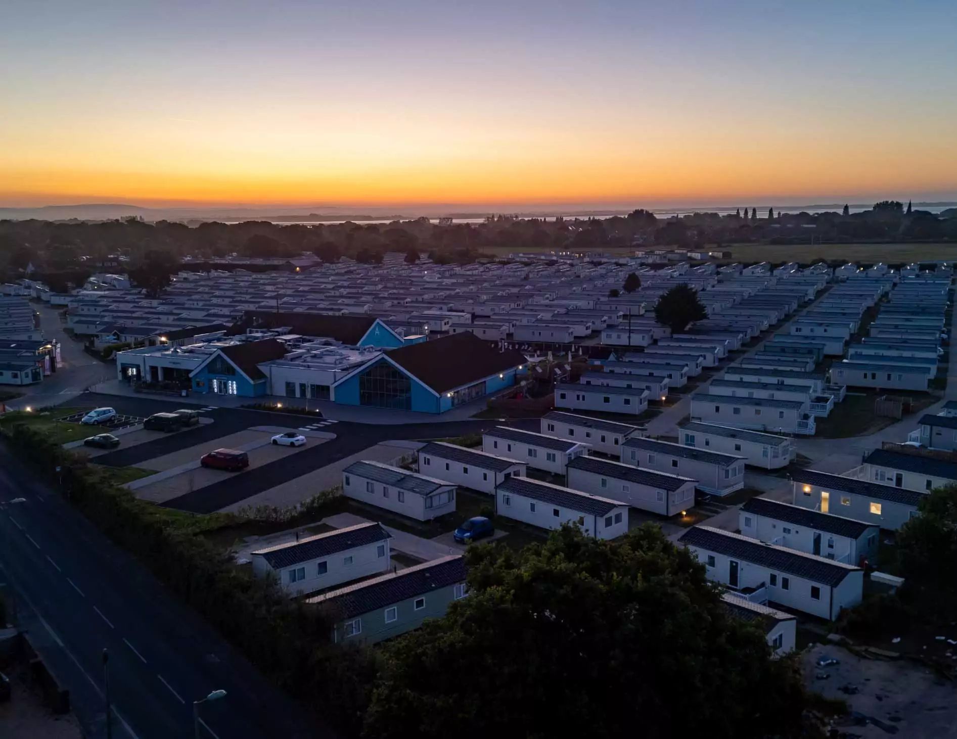 Aerial view of the holiday park at sunset with rows of caravans and the main building at Billing Aquadrome.