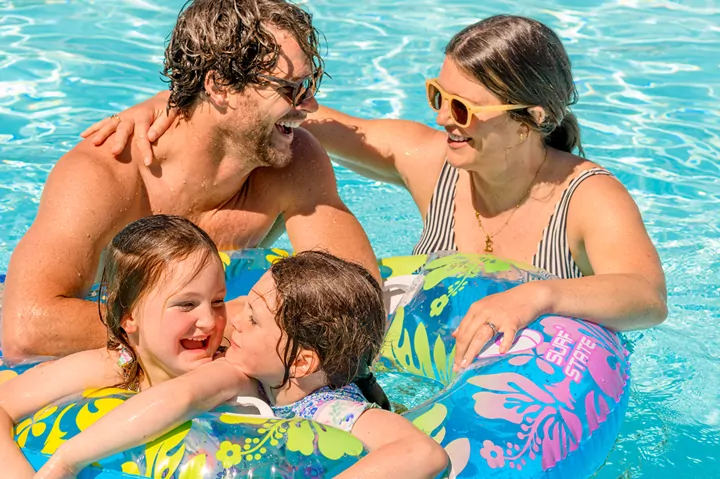 Family enjoying time together in an outdoor swimming pool with inflatable rings, Hayling Island