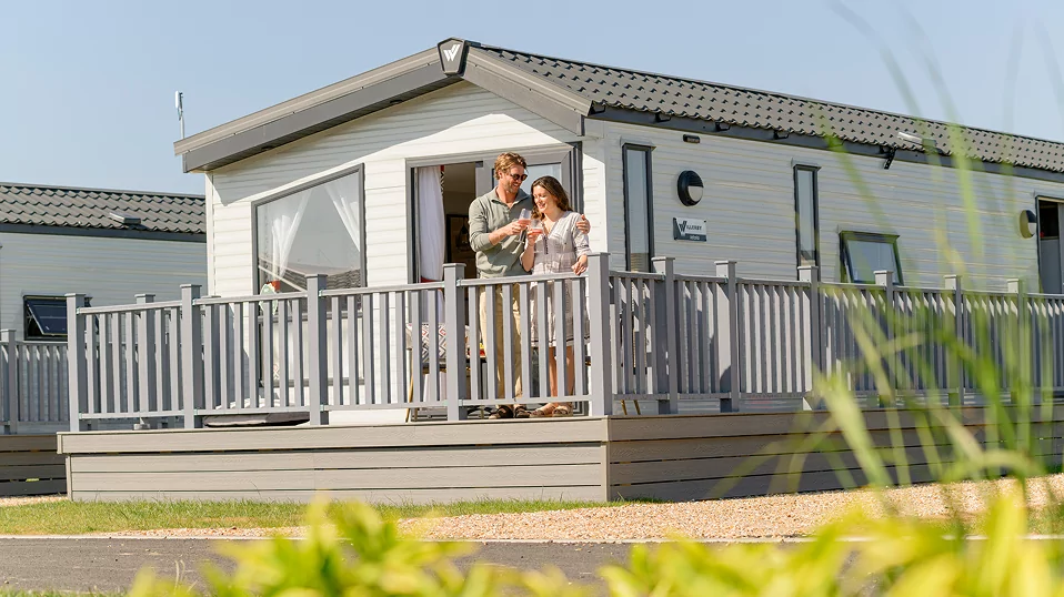 Guests relaxing on the decking outside a holiday lodge enjoying the sunshine and outdoor space at Hayling Island.