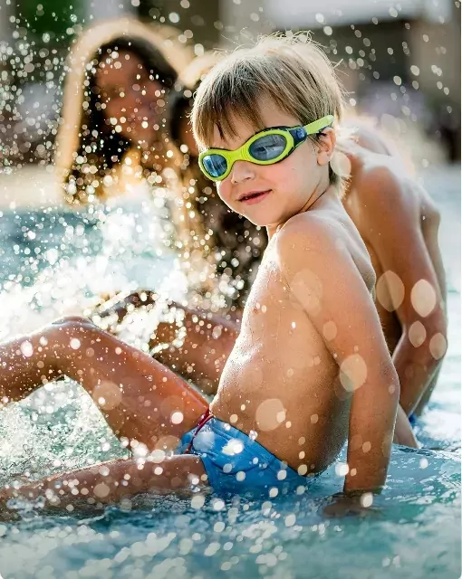 Young boy splashing in an outdoor pool with goggles on, enjoying summer fun at Hollybush farm.