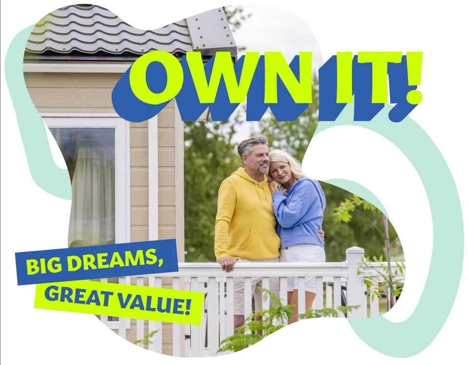 Smiling couple standing on a holiday home decking, embracing the dream of ownership with “Own It!” text and vibrant promotional graphics.