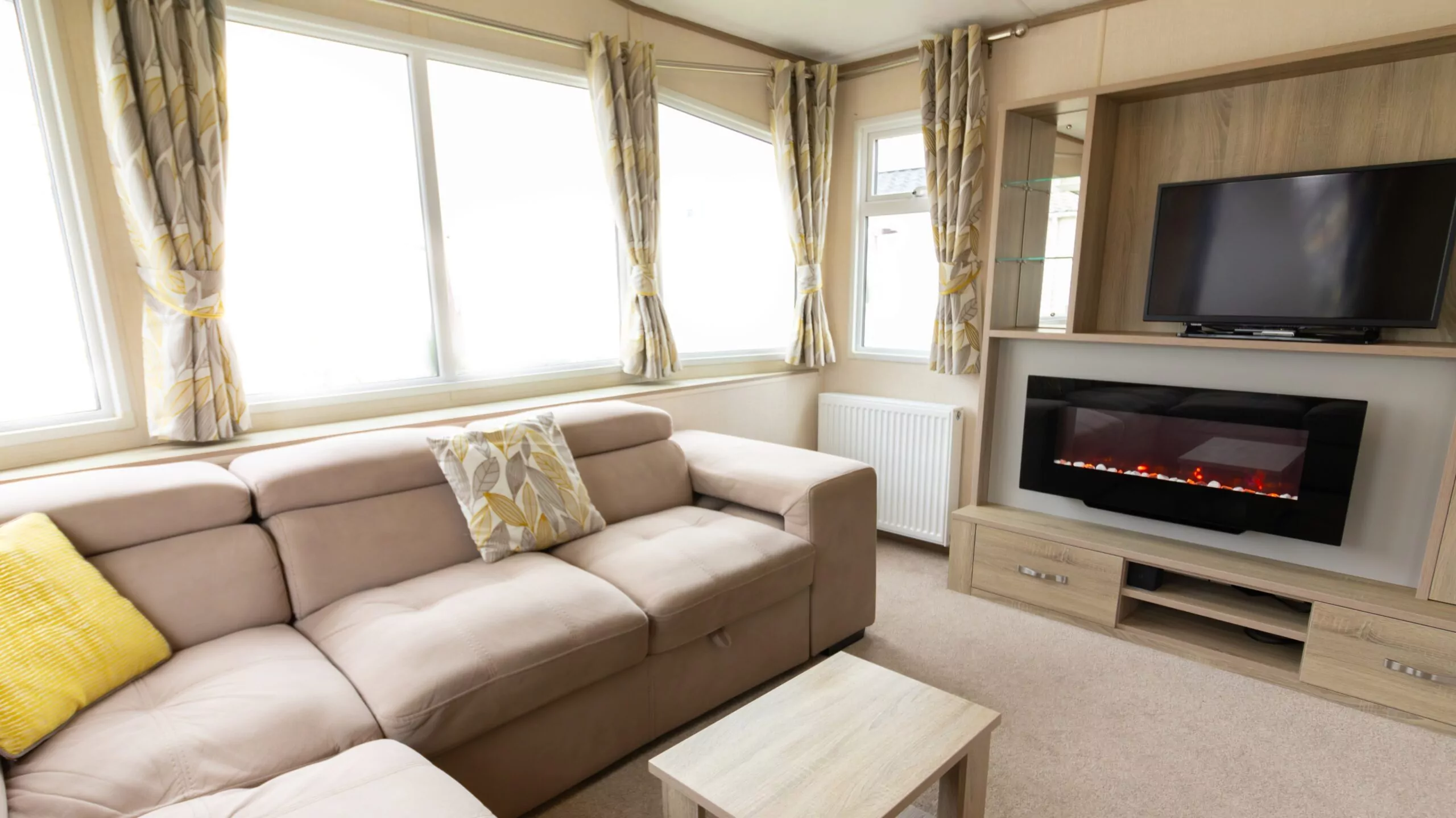 Cozy lounge inside a gold grade caravan with modern fireplace and TV