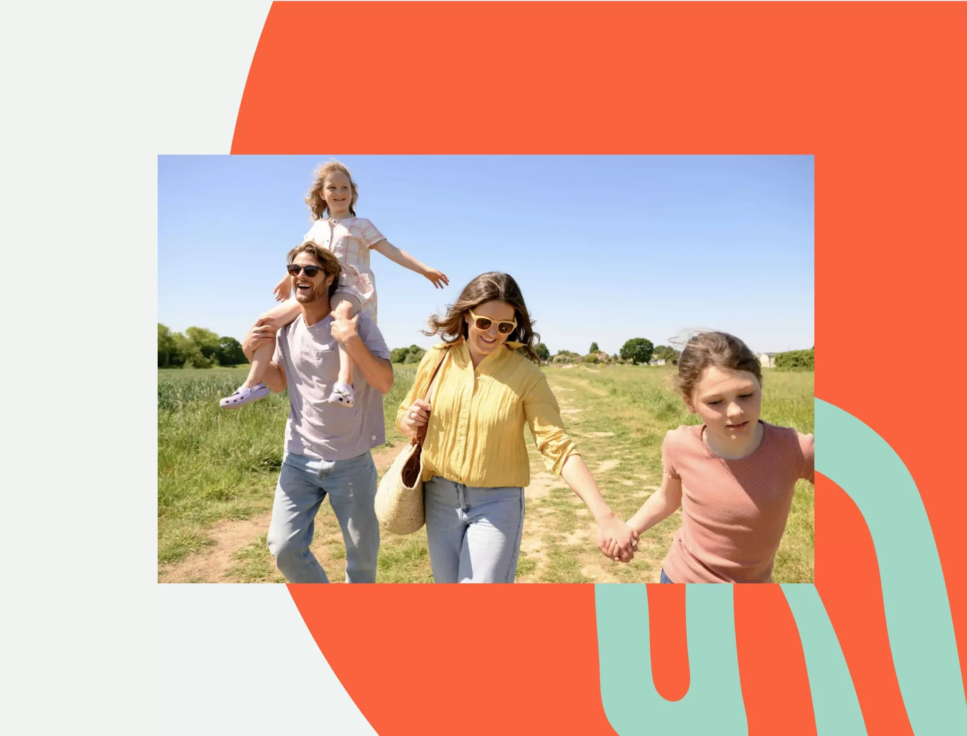 Family enjoying a countryside walk on a bright sunny day, with a young girl on her father’s shoulders and everyone smiling as they stroll along a rural path.