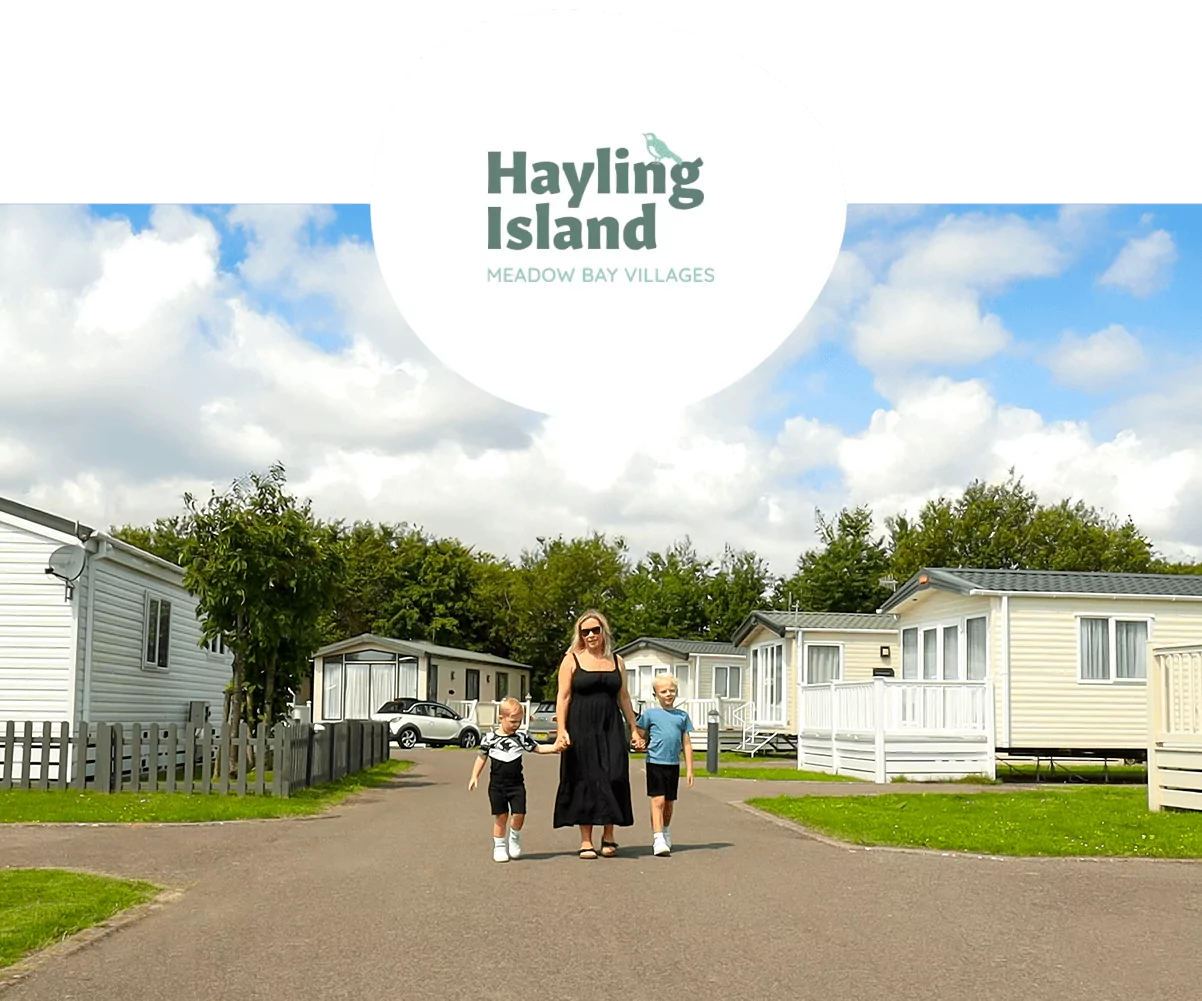 Mother and two children walking through Meadow Bay Villages’ Hayling Island holiday park on a sunny day.