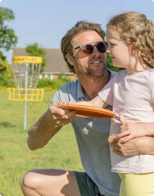Parent teaching their young child how to throw a frisbee