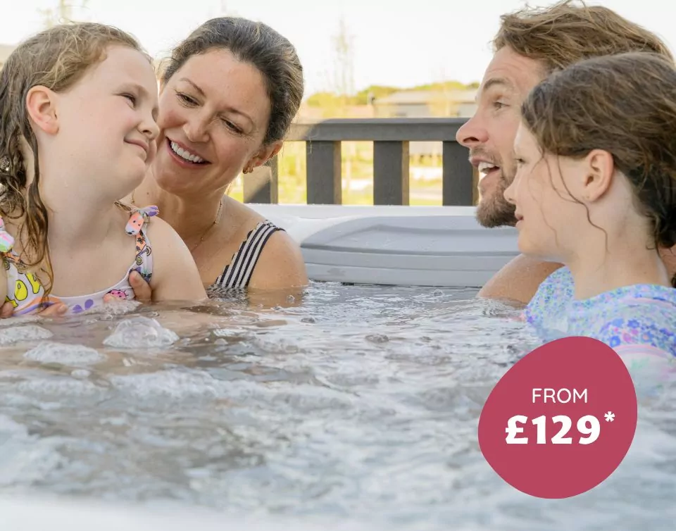 Smiling parents and children relaxing together in a hot tub at Meadow Bay Villages.