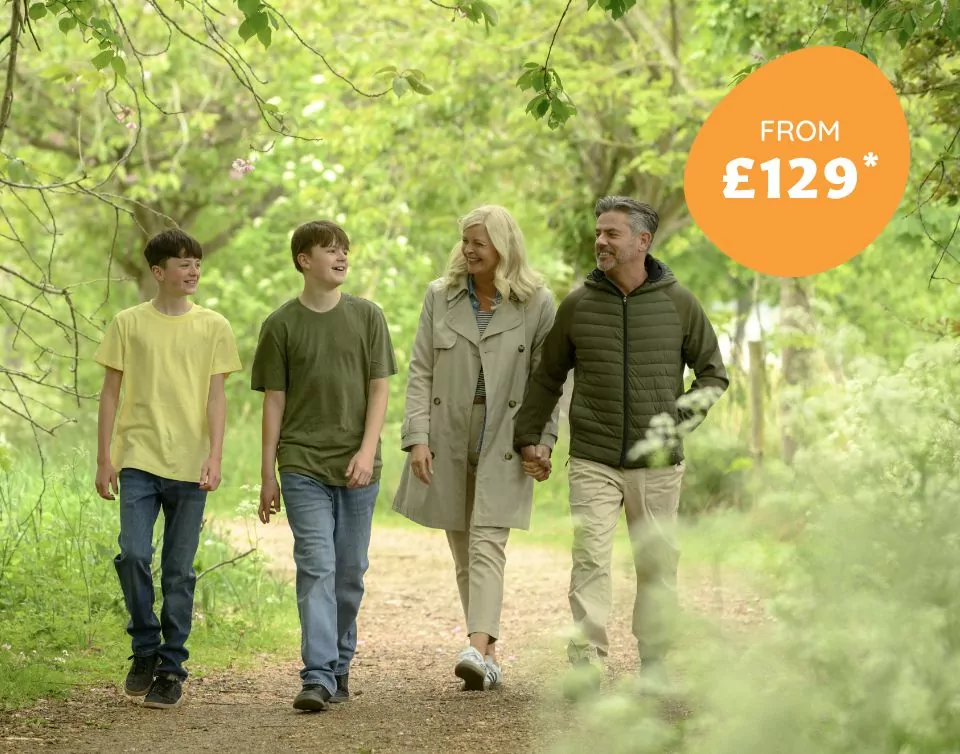 Family walking happily together through a green woodland trail, enjoying outdoor holidays at Meadow Bay Villages.