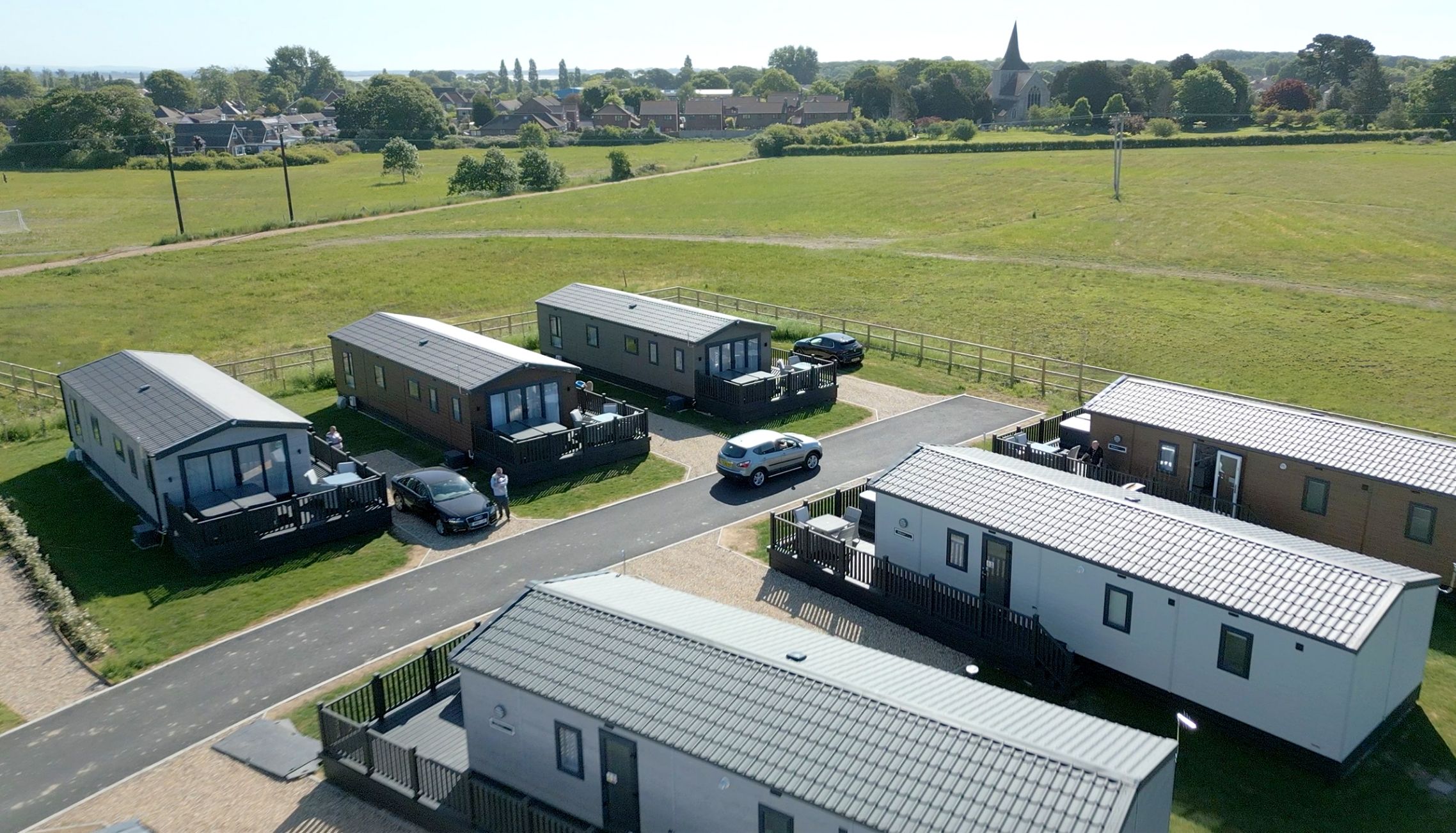 Aerial view of modern holiday homes arranged along quiet roads with open countryside surroundings at Meadow Bay Villages