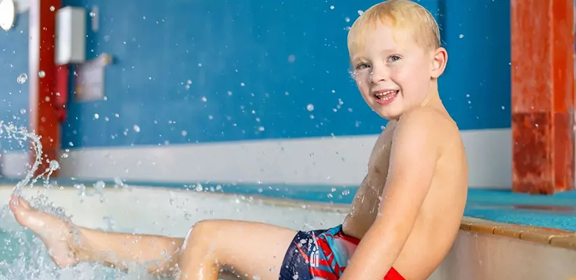 Toddler enjoying a splash at the edge of a swimming pool during a family holiday at Meadow Bay Villages