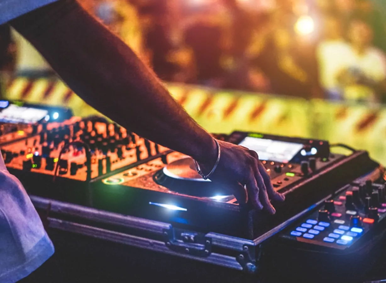 DJ performing live on stage with professional mixing equipment during a music festival event, Meadow Bay Villages