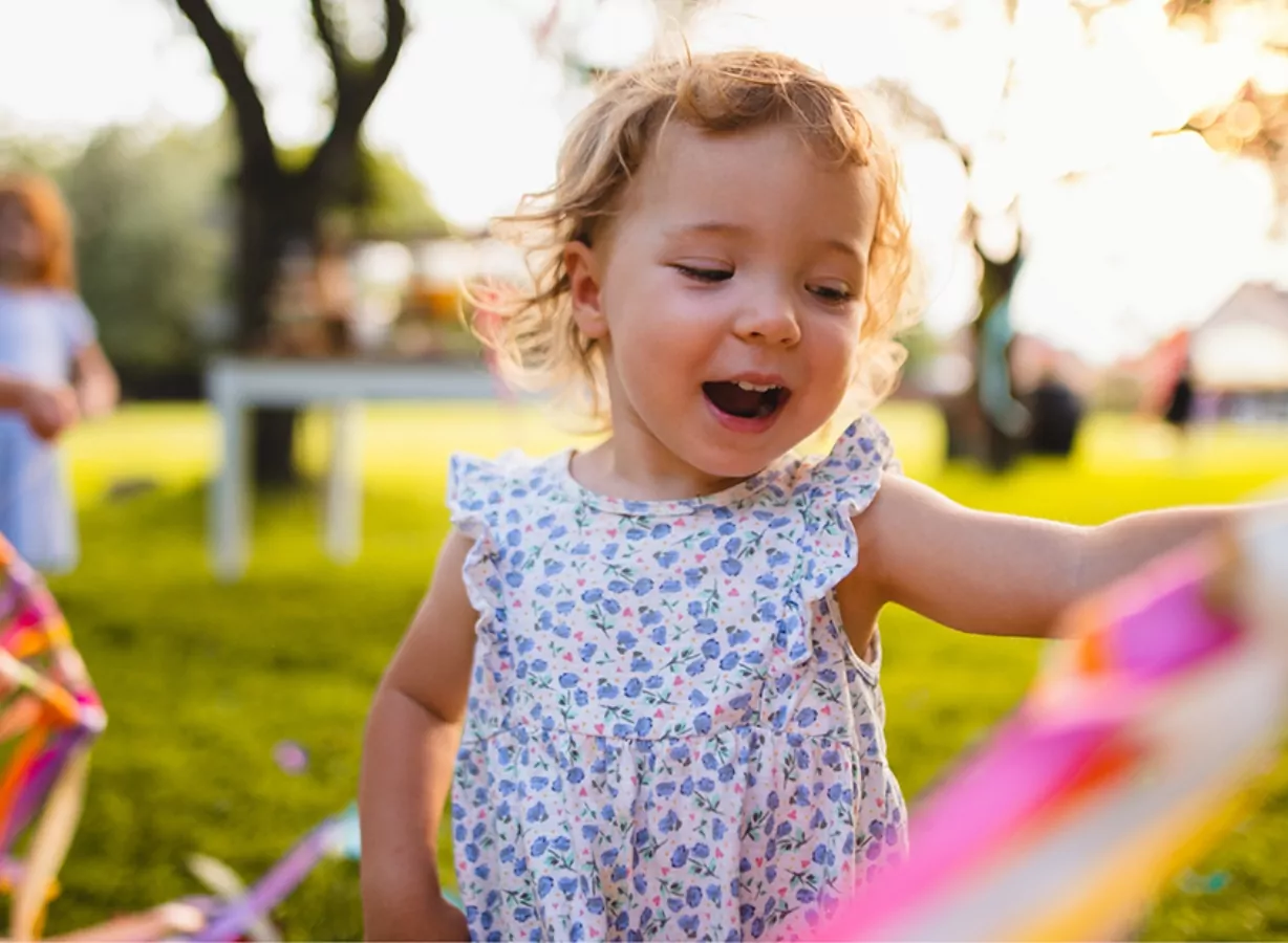 Smiling toddler enjoying outdoor play on the grass during a family-friendly holiday experience, Meadow Bay Villages