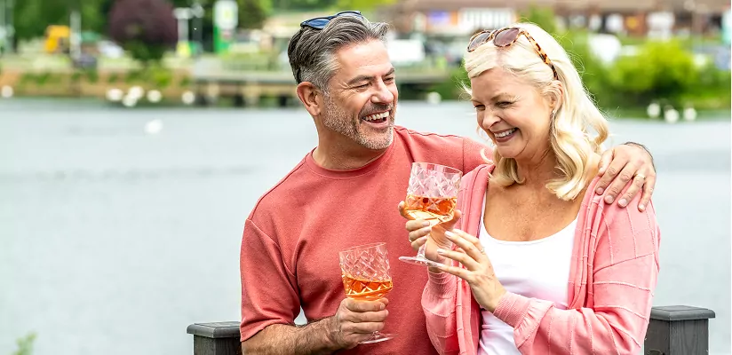 Couple relaxing with drinks beside the water during a peaceful break at Meadow Bay Villages