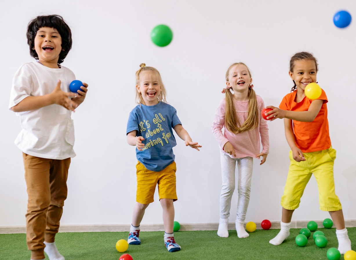 Children laughing and playing interactive ball games together during a fun indoor kids activity session, Meadow Bay Villages.