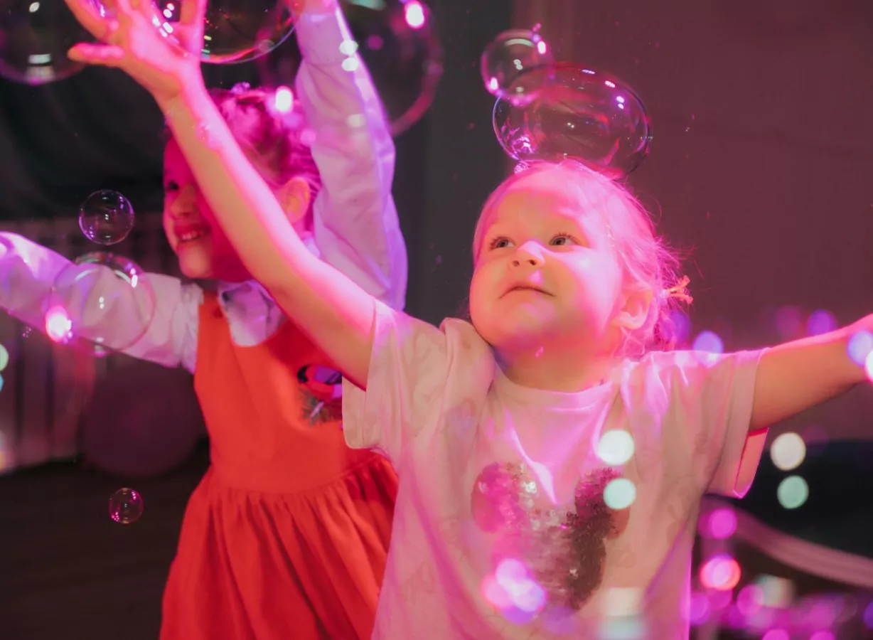 Children reaching for bubbles during a colourful sensory celebration session designed for inclusive fun and engagement, Meadow Bay Villages.