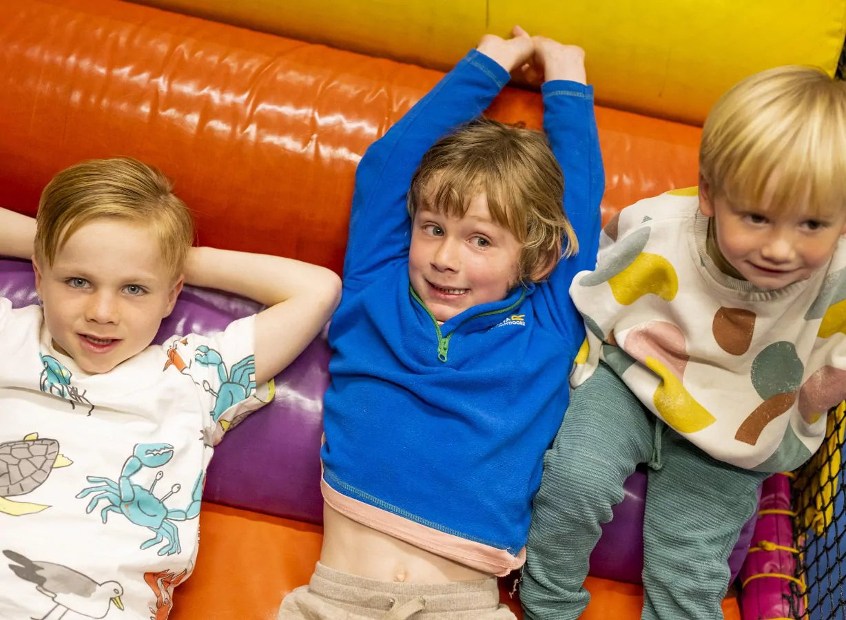 Children relaxing and playing together inside a colourful indoor soft play area, Meadow Bay Villages.