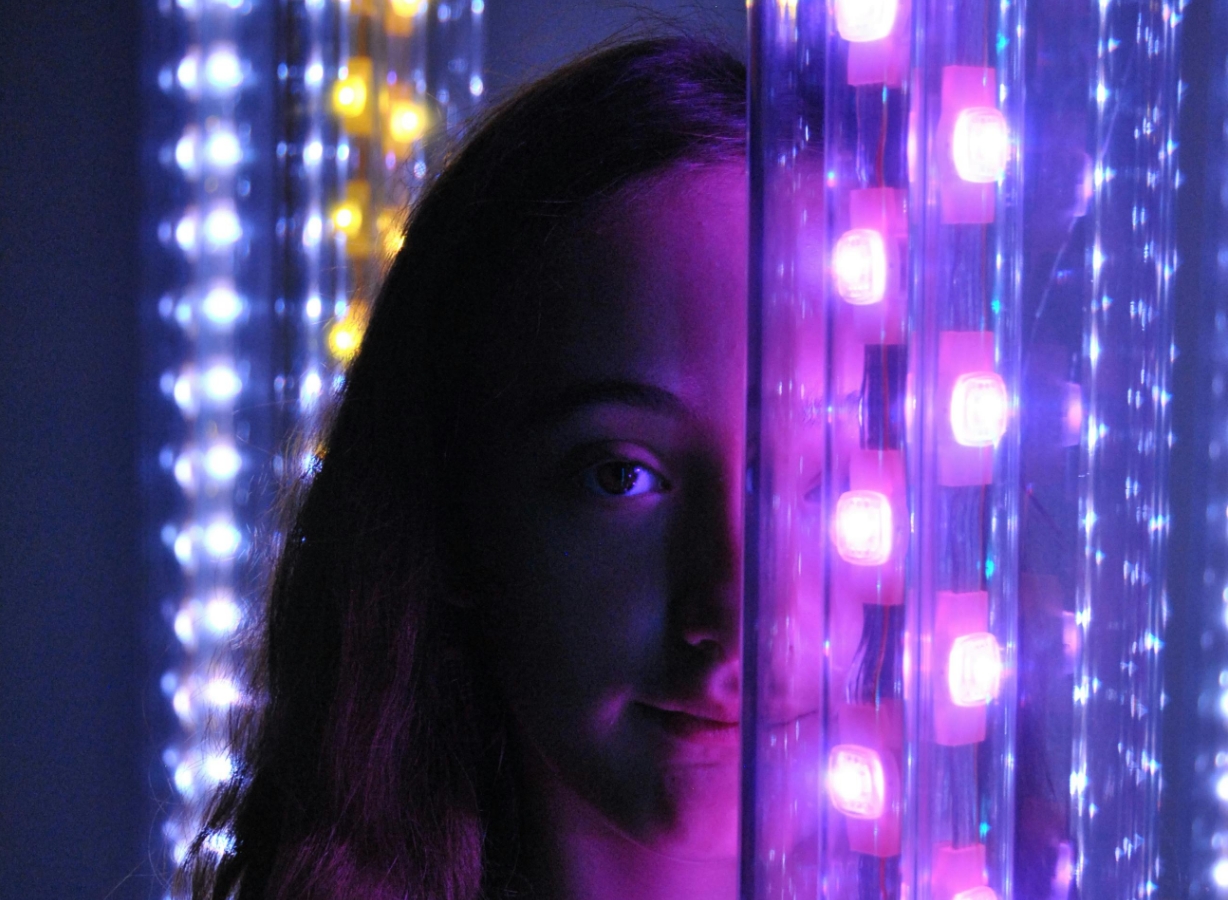 Guest enjoying a calming twilight sensory disco surrounded by soft glowing lights in a sensory-friendly environment, Meadow Bay Villages.