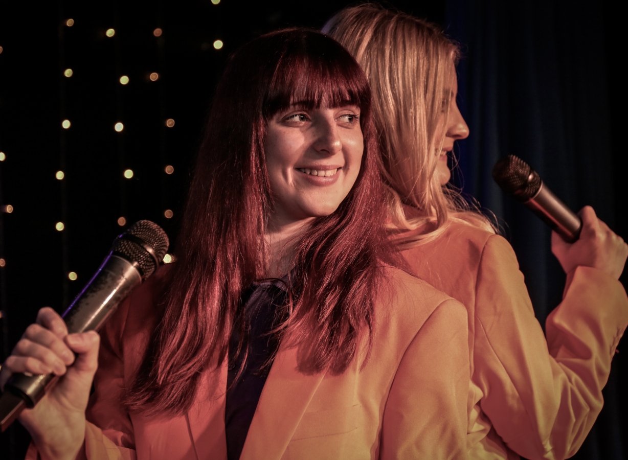 Two performers holding microphones on stage during an inclusive entertainment performance designed for accessible showtimes, Meadow Bay Villages.