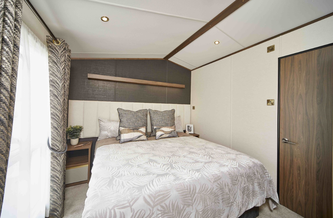 Comfortable caravan bedroom with double bed and contemporary furnishings at Meadow Bay Villages