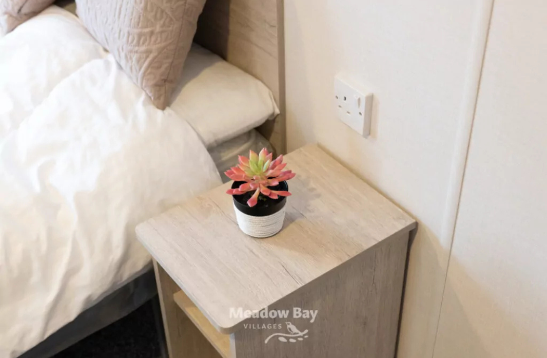 Cosy bedroom with bedside table and decorative plant at Meadow Bay Villages